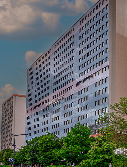 Façade de l'hôtel FirstName Toulouse illuminée à la tombée de la nuit, mettant en valeur son architecture moderne et élégante